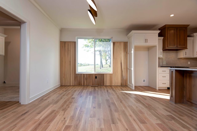 kitchen featuring light hardwood / wood-style floors, ornamental molding, decorative backsplash, and white cabinets