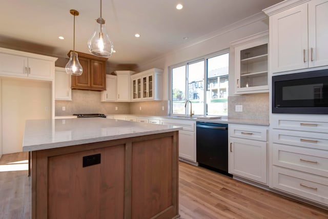 kitchen featuring hanging light fixtures, backsplash, black appliances, a center island, and white cabinets