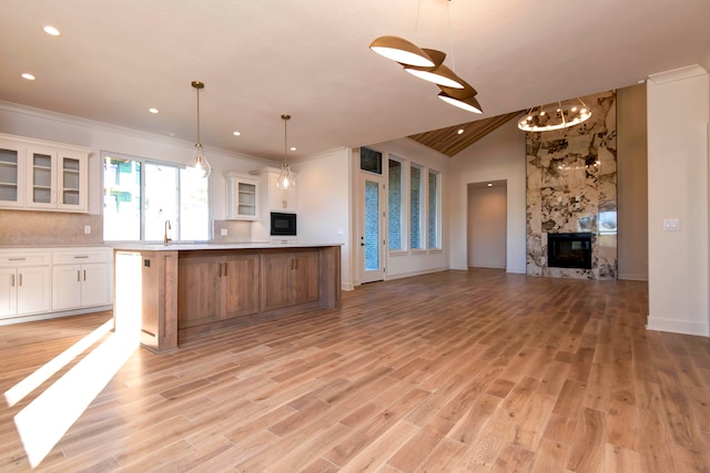 kitchen with a spacious island, white cabinetry, hanging light fixtures, and light wood-type flooring