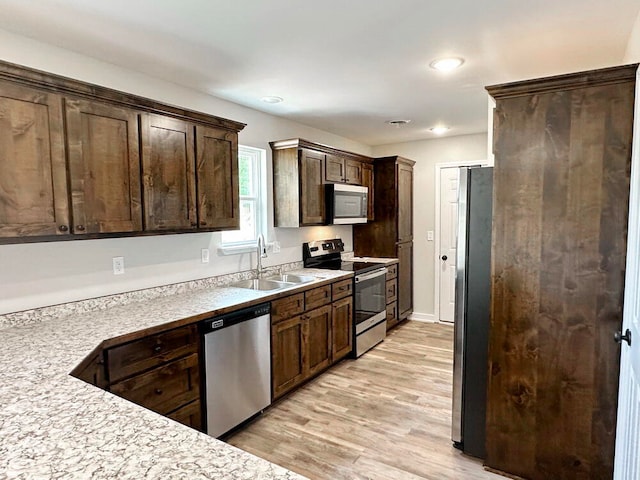 kitchen featuring appliances with stainless steel finishes, sink, dark brown cabinets, and light wood-type flooring