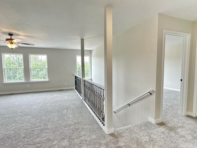 stairs featuring ceiling fan and carpet flooring