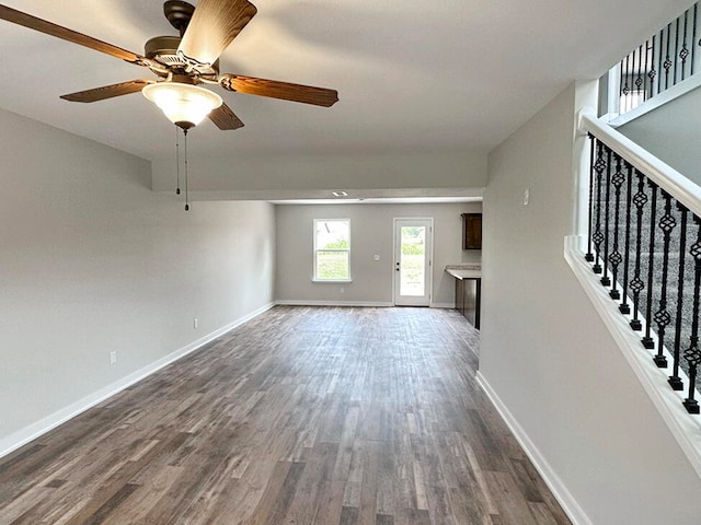 unfurnished living room with dark wood-type flooring and ceiling fan