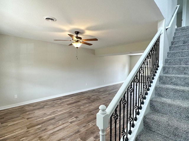 stairs featuring ceiling fan and hardwood / wood-style floors