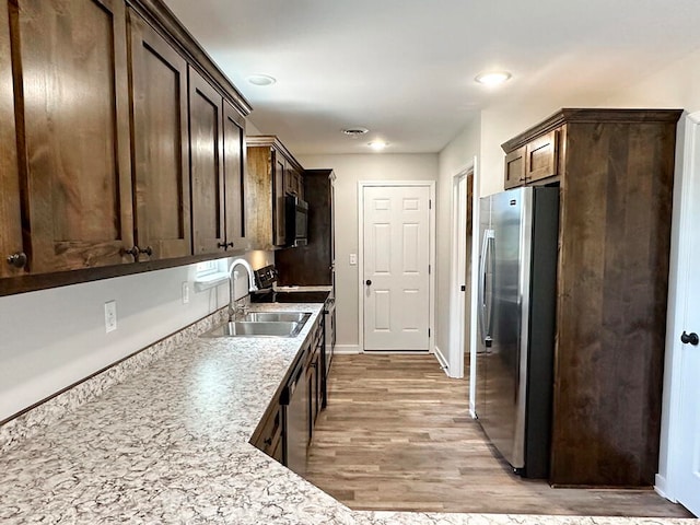 kitchen with light hardwood / wood-style floors, dark brown cabinetry, stainless steel appliances, and sink