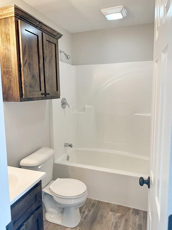 full bathroom featuring toilet, hardwood / wood-style floors, vanity, and bathing tub / shower combination