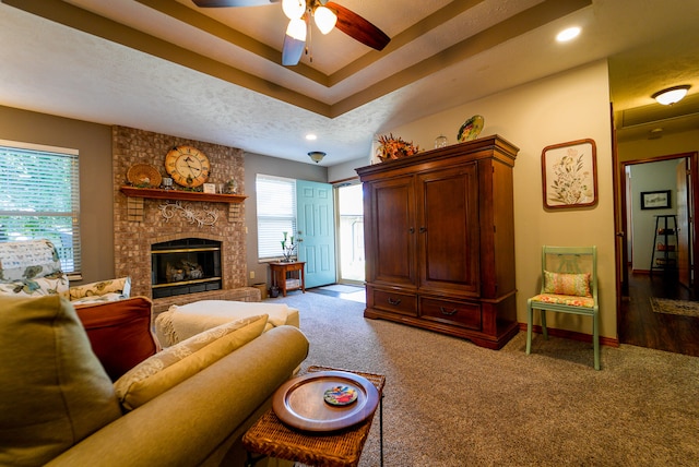 living room featuring a large fireplace, a textured ceiling, hardwood / wood-style floors, and ceiling fan