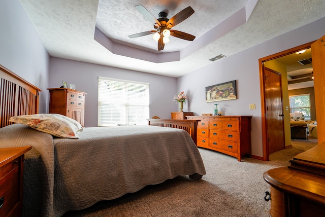 bedroom with ceiling fan, light carpet, a textured ceiling, and a raised ceiling