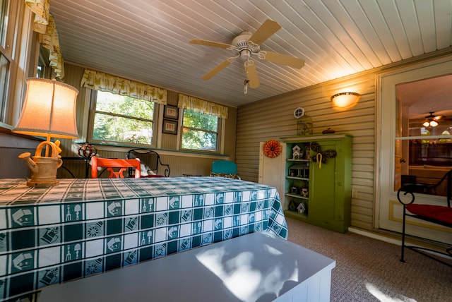 bedroom with wooden walls, carpet floors, and ceiling fan