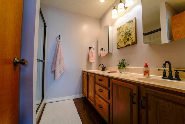 bathroom featuring vanity, a textured ceiling, hardwood / wood-style flooring, and a shower with shower door