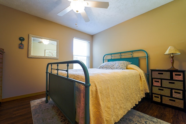 bedroom with a textured ceiling, dark wood-type flooring, and ceiling fan