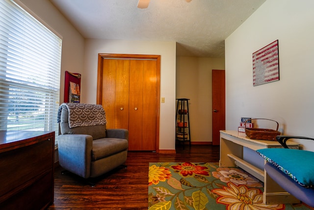 living area with dark hardwood / wood-style floors, a textured ceiling, and ceiling fan