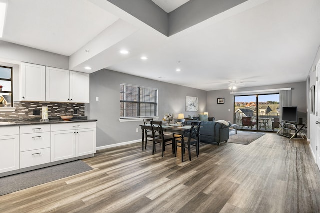 kitchen with white cabinetry, ceiling fan, wood-type flooring, and backsplash