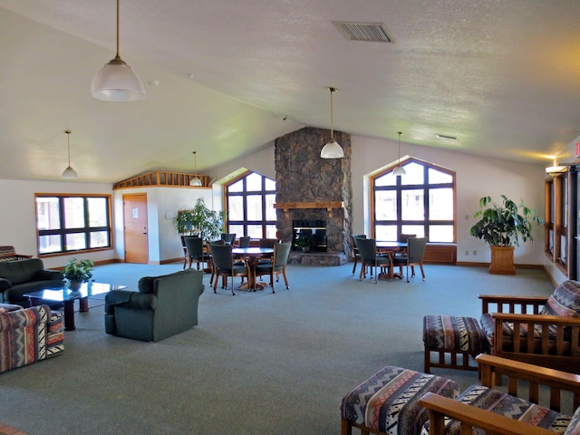 carpeted living room featuring vaulted ceiling, a stone fireplace, a textured ceiling, and a healthy amount of sunlight