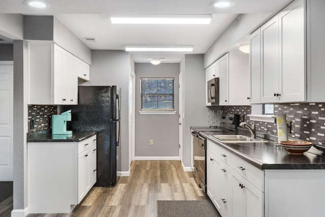 kitchen featuring decorative backsplash, white cabinetry, stainless steel appliances, and wood-type flooring