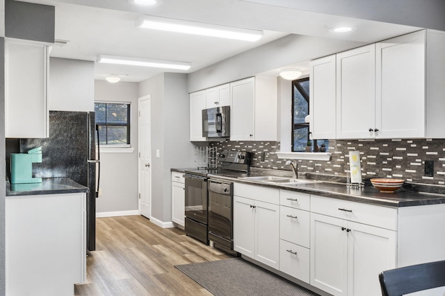 kitchen with sink, black appliances, light wood-type flooring, white cabinets, and tasteful backsplash