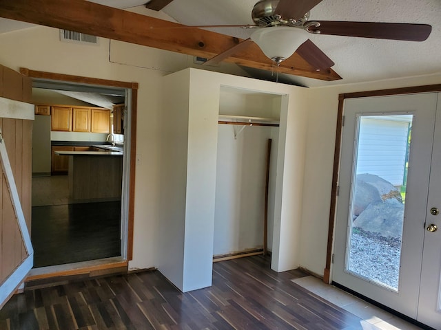 unfurnished bedroom featuring dark wood-type flooring, stainless steel refrigerator, multiple windows, and sink