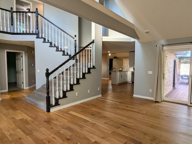 stairway with hardwood / wood-style flooring and high vaulted ceiling