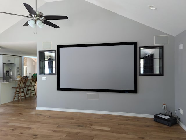 cinema room with light hardwood / wood-style flooring, high vaulted ceiling, and ceiling fan