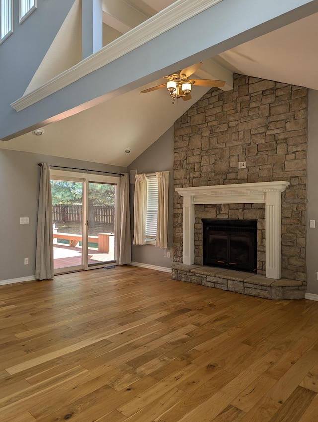 unfurnished living room with a stone fireplace, high vaulted ceiling, ceiling fan, and light wood-type flooring