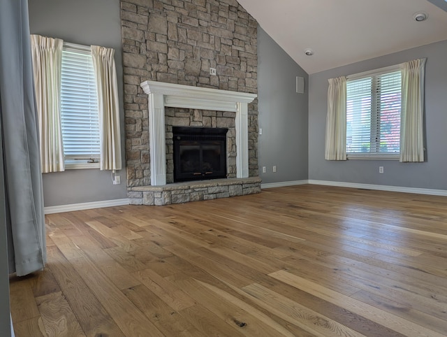 unfurnished living room featuring high vaulted ceiling, a fireplace, and light hardwood / wood-style floors