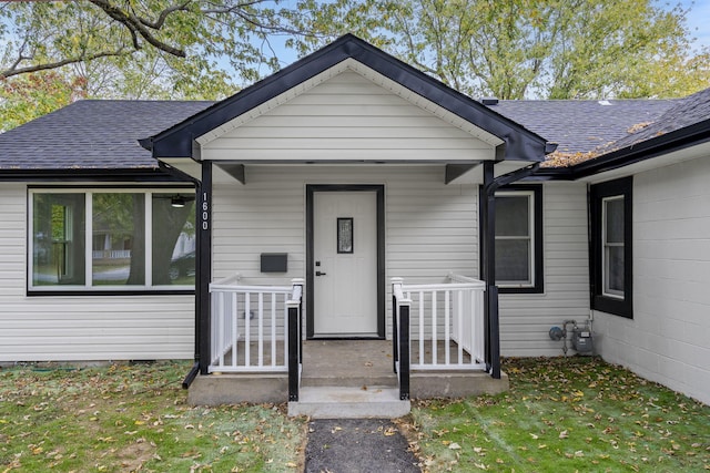 doorway to property featuring a lawn and a porch