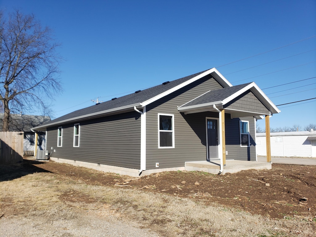 view of front facade featuring roof with shingles, a patio, and central AC unit