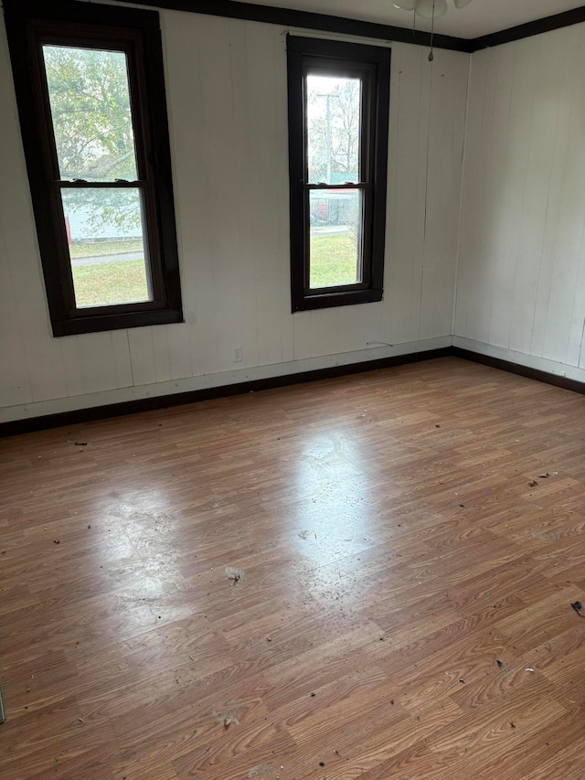 unfurnished room with wood walls, ceiling fan, and light hardwood / wood-style flooring