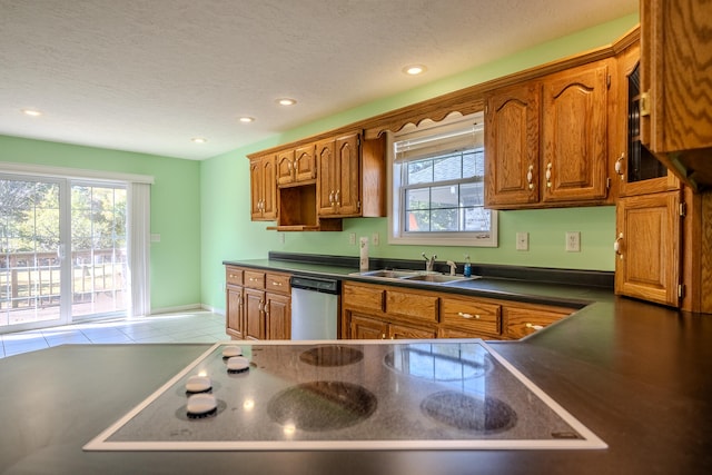 kitchen featuring a textured ceiling, stainless steel dishwasher, light tile patterned flooring, black electric stovetop, and sink