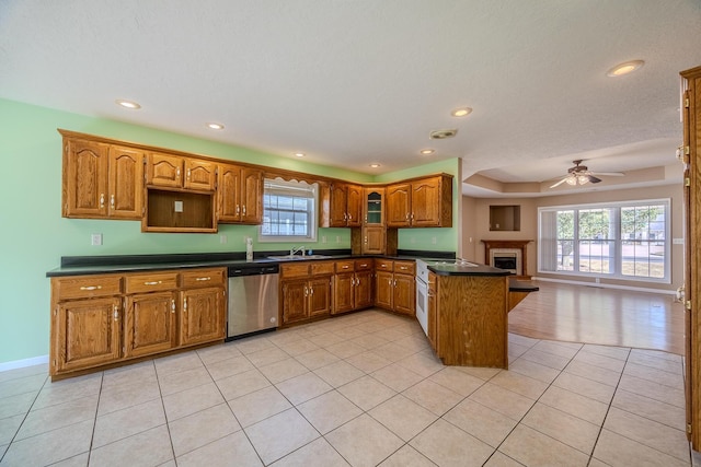 kitchen with a peninsula, a sink, dark countertops, ceiling fan, and dishwasher