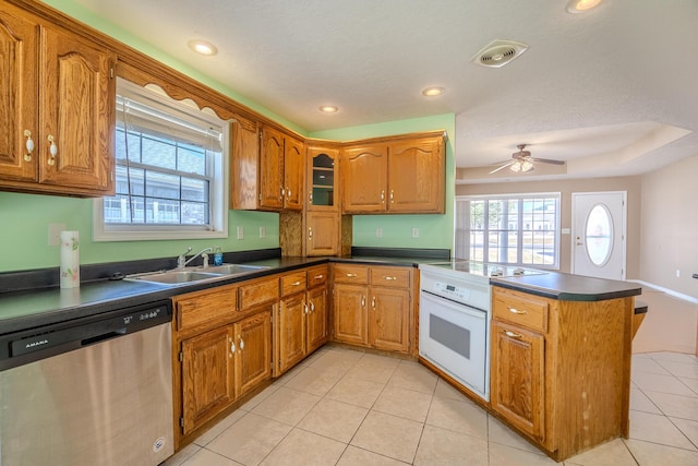 kitchen featuring dark countertops, electric stove, stainless steel dishwasher, a sink, and a peninsula