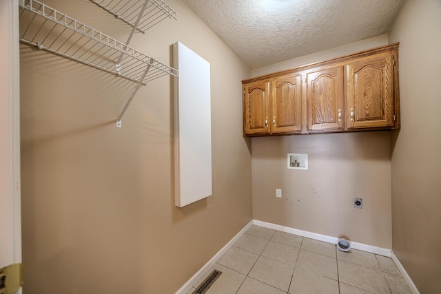 laundry area featuring baseboards, hookup for a washing machine, cabinet space, electric dryer hookup, and light tile patterned floors