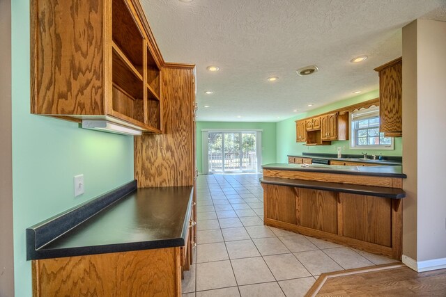 kitchen with a peninsula, a textured ceiling, dark countertops, recessed lighting, and open shelves