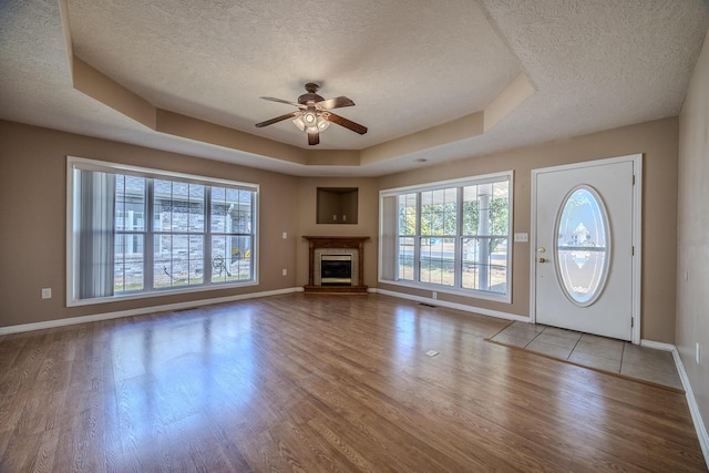 unfurnished living room featuring ceiling fan, baseboards, wood finished floors, and a textured ceiling