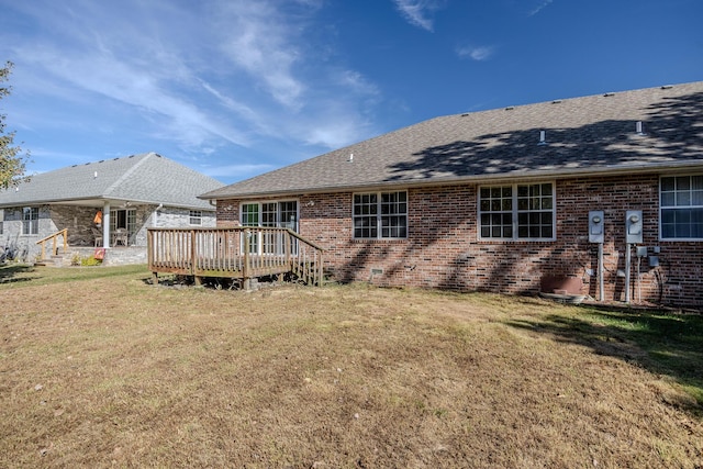 back of house with brick siding, a lawn, a shingled roof, and a wooden deck