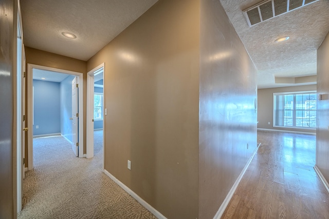 hall with light hardwood / wood-style flooring and a textured ceiling