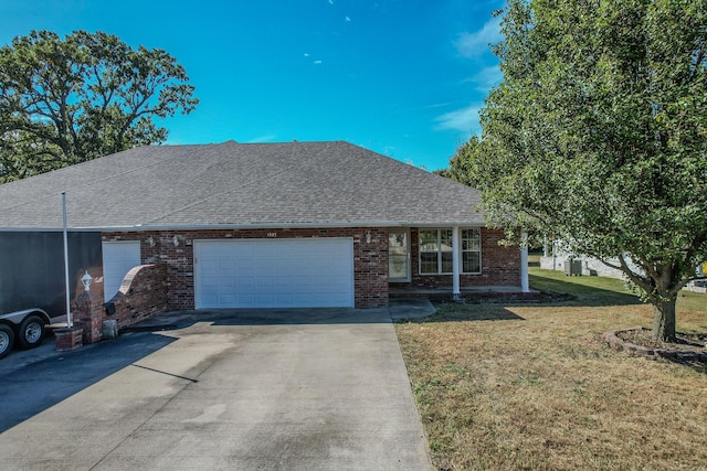 ranch-style house with a shingled roof, brick siding, a front yard, and concrete driveway