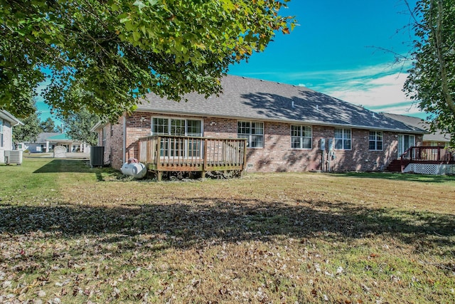 back of property with a wooden deck, a yard, central air condition unit, and brick siding