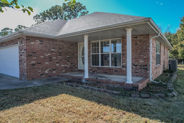 ranch-style house featuring an attached garage, brick siding, a porch, and central AC unit