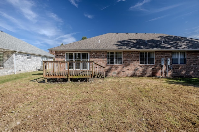 rear view of property featuring brick siding, a lawn, a shingled roof, and a deck