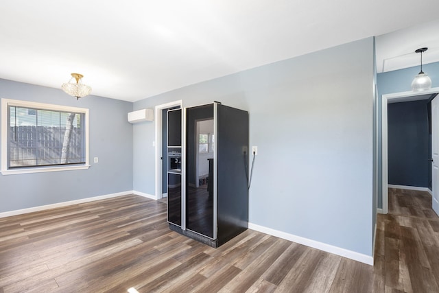 unfurnished room with dark wood-type flooring and a wall mounted air conditioner