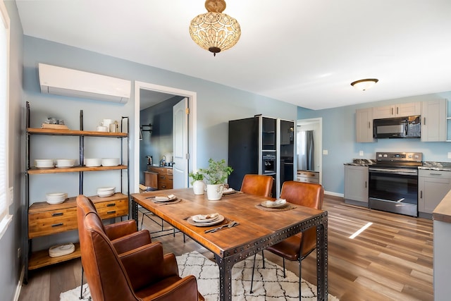 dining area featuring a wall mounted AC and light hardwood / wood-style flooring