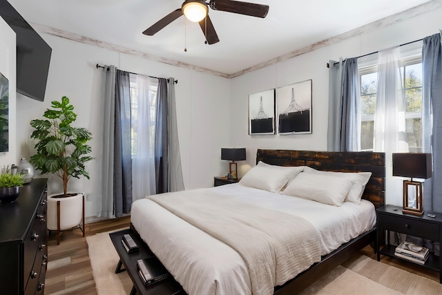 bedroom with crown molding, hardwood / wood-style flooring, and ceiling fan