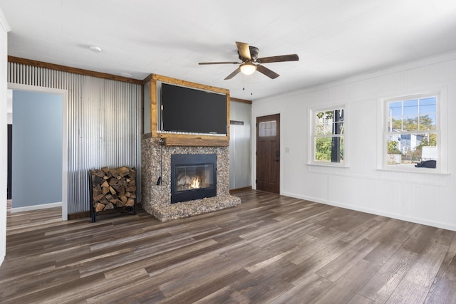 unfurnished living room with dark wood-type flooring, crown molding, and ceiling fan