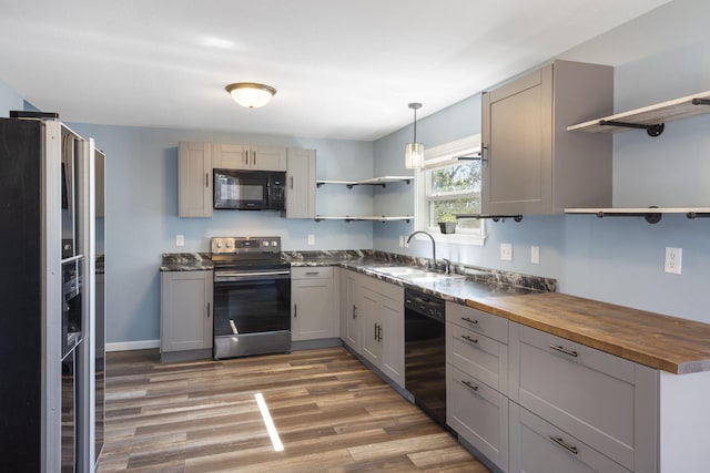 kitchen with dark hardwood / wood-style flooring, black appliances, gray cabinets, wooden counters, and sink