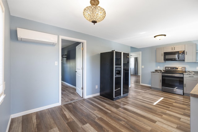 kitchen featuring gray cabinets, a wall mounted air conditioner, black appliances, and dark hardwood / wood-style floors