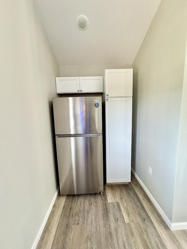 kitchen with freestanding refrigerator, white cabinets, and light wood-style floors