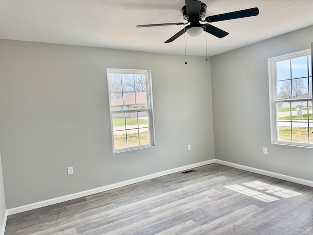 spare room with baseboards, a healthy amount of sunlight, and wood finished floors