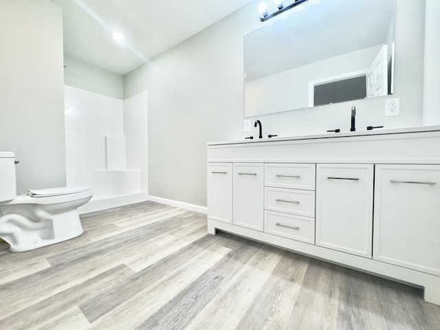 full bath with a sink, wood finished floors, toilet, and double vanity