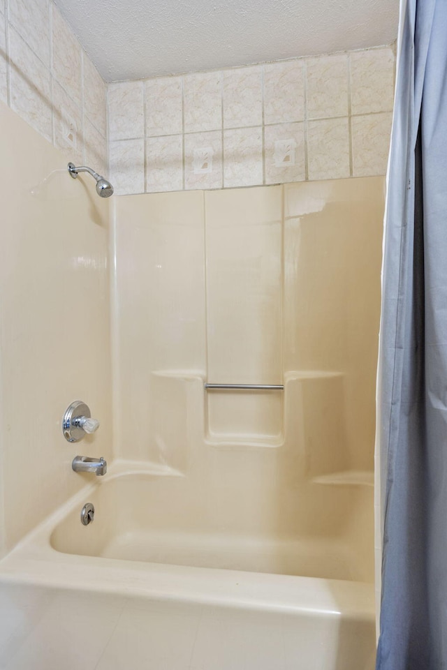 bathroom with a textured ceiling and shower / bath combo with shower curtain