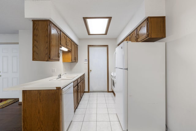 kitchen with kitchen peninsula, white appliances, sink, and light tile patterned floors